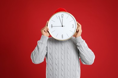 Photo of Man with clock on red background. New Year countdown