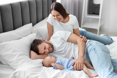 Photo of Happy family. Parents with their cute baby on bed indoors