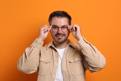 Photo of Portrait of man in stylish glasses on orange background