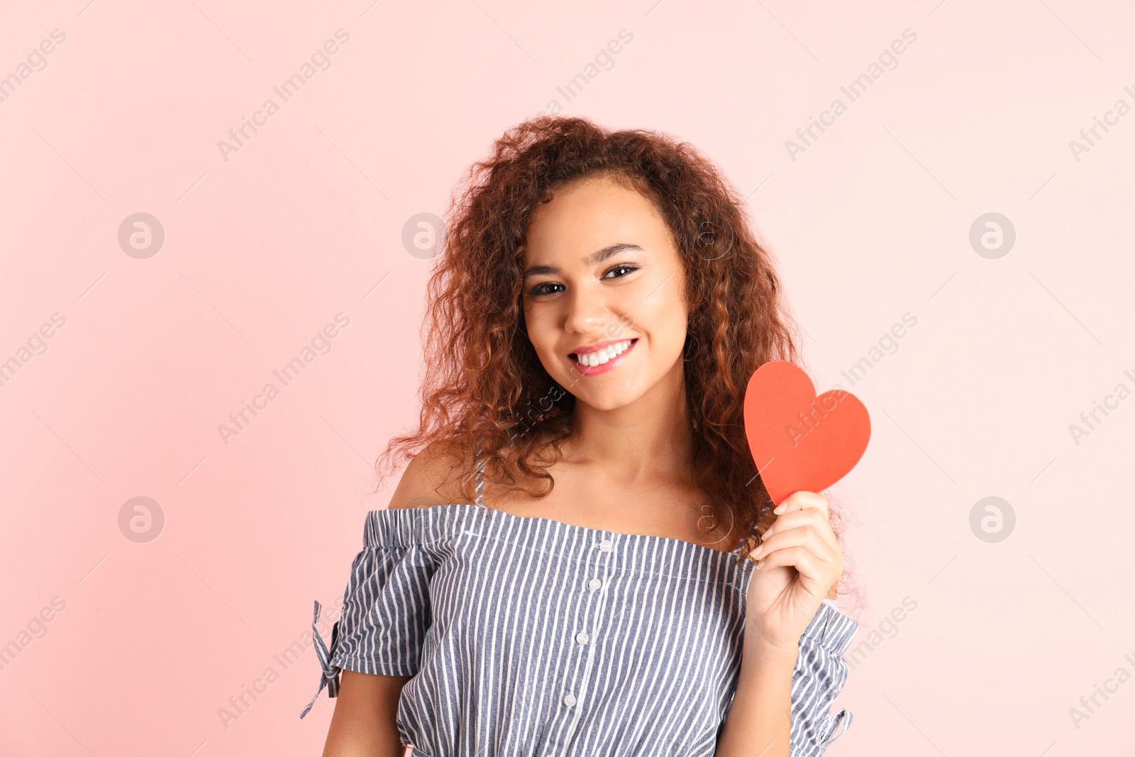 Photo of African-American woman with paper heart on color background