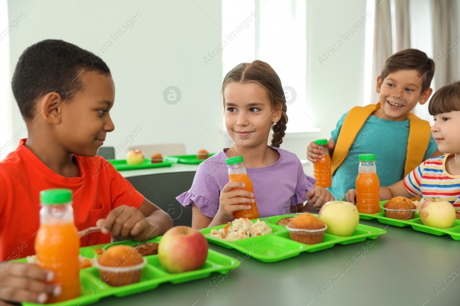 Photo of Children sitting at table and eating healthy food during break at school