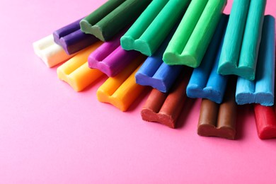 Photo of Stacked colorful plasticine on pink background, closeup