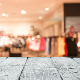 Image of Empty wooden table and blurred view of store with modern clothes