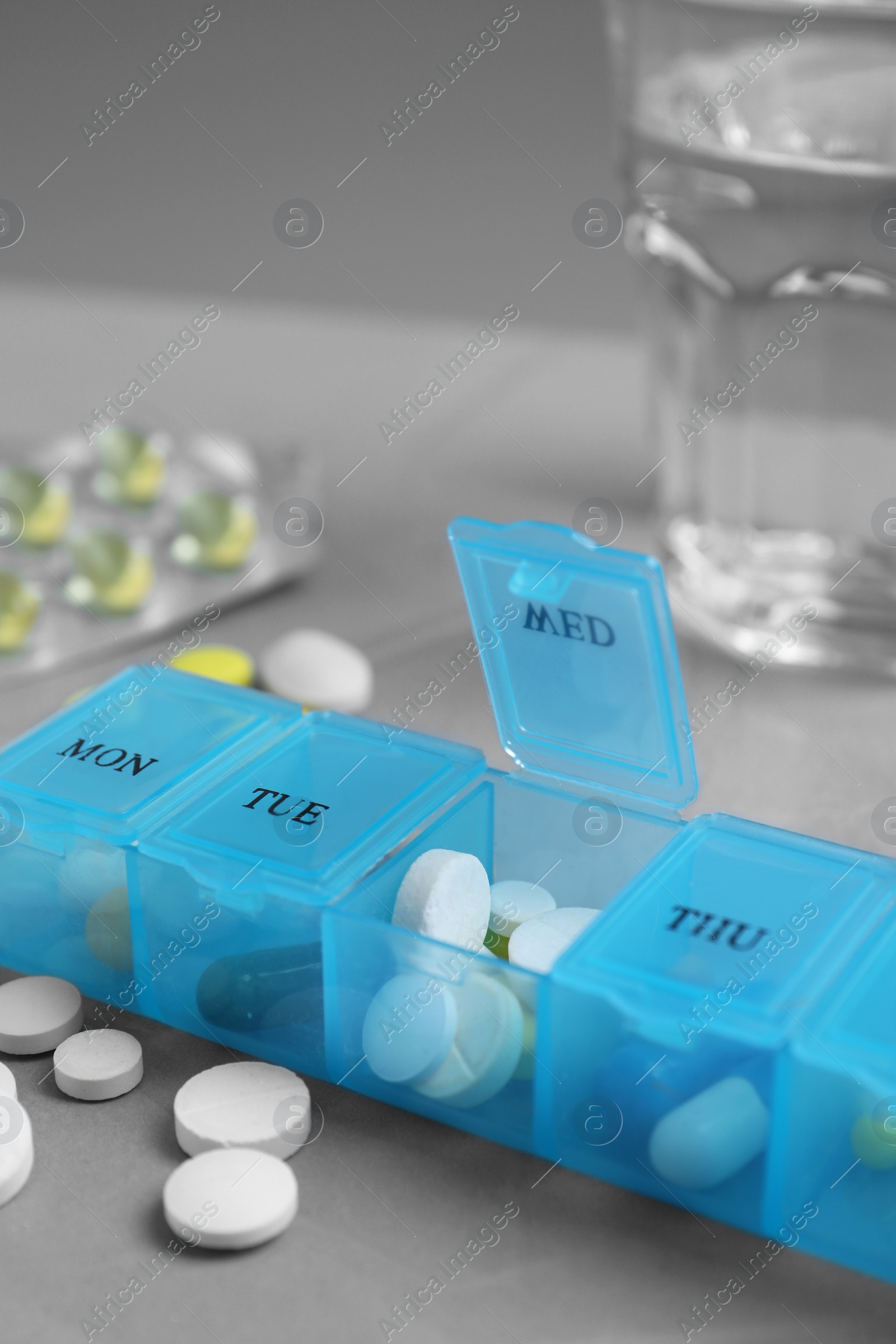 Photo of Weekly pill box with medicaments on grey table, closeup