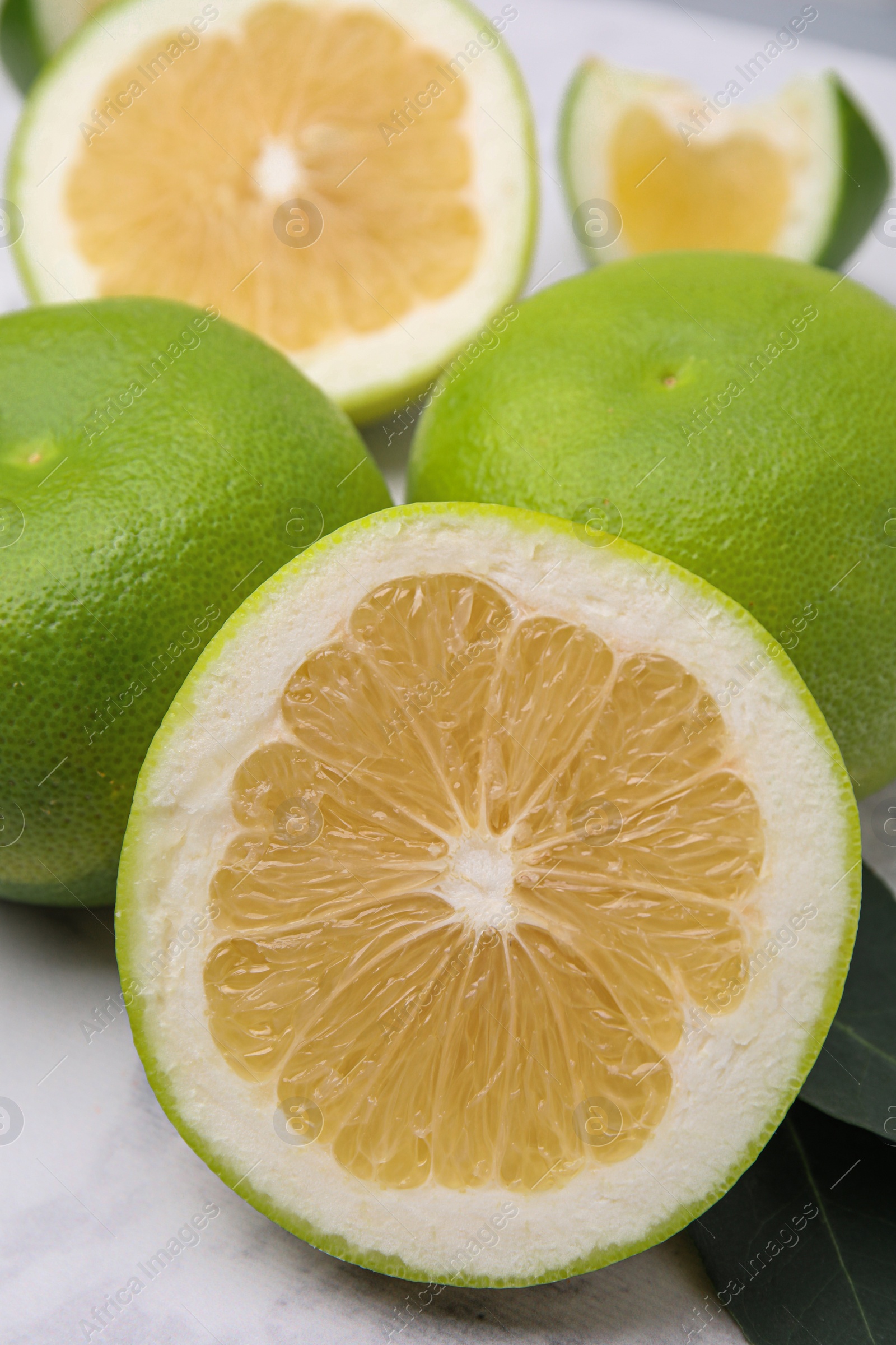 Photo of Whole and cut sweetie fruits on white table, closeup