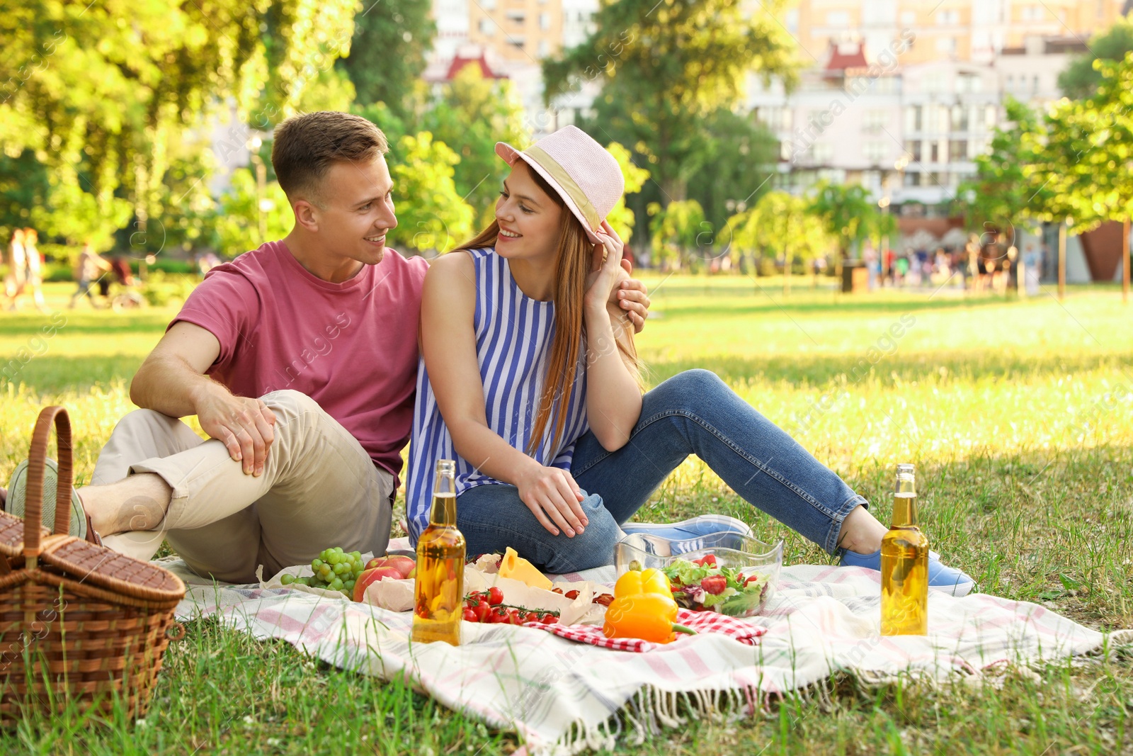 Photo of Young couple enjoying picnic in park on summer day