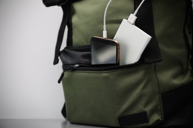 Photo of Smartphone charging with power bank in backpack on table, closeup