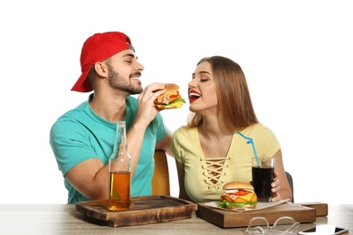 Photo of Happy couple having lunch with burgers at table on white background