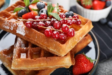Photo of Delicious Belgian waffles with berries and powdered sugar on table, closeup