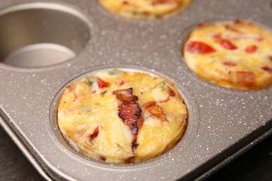 Photo of Freshly baked bacon and egg muffins with cheese in tin, closeup