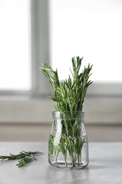 Photo of Jar with fresh rosemary twigs on table