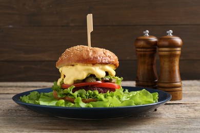 Photo of Delicious vegetarian burger served on wooden table