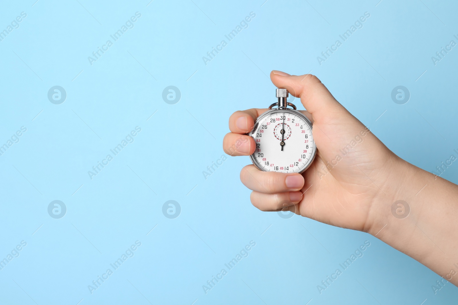 Photo of Woman holding vintage timer on light blue background, closeup. Space for text