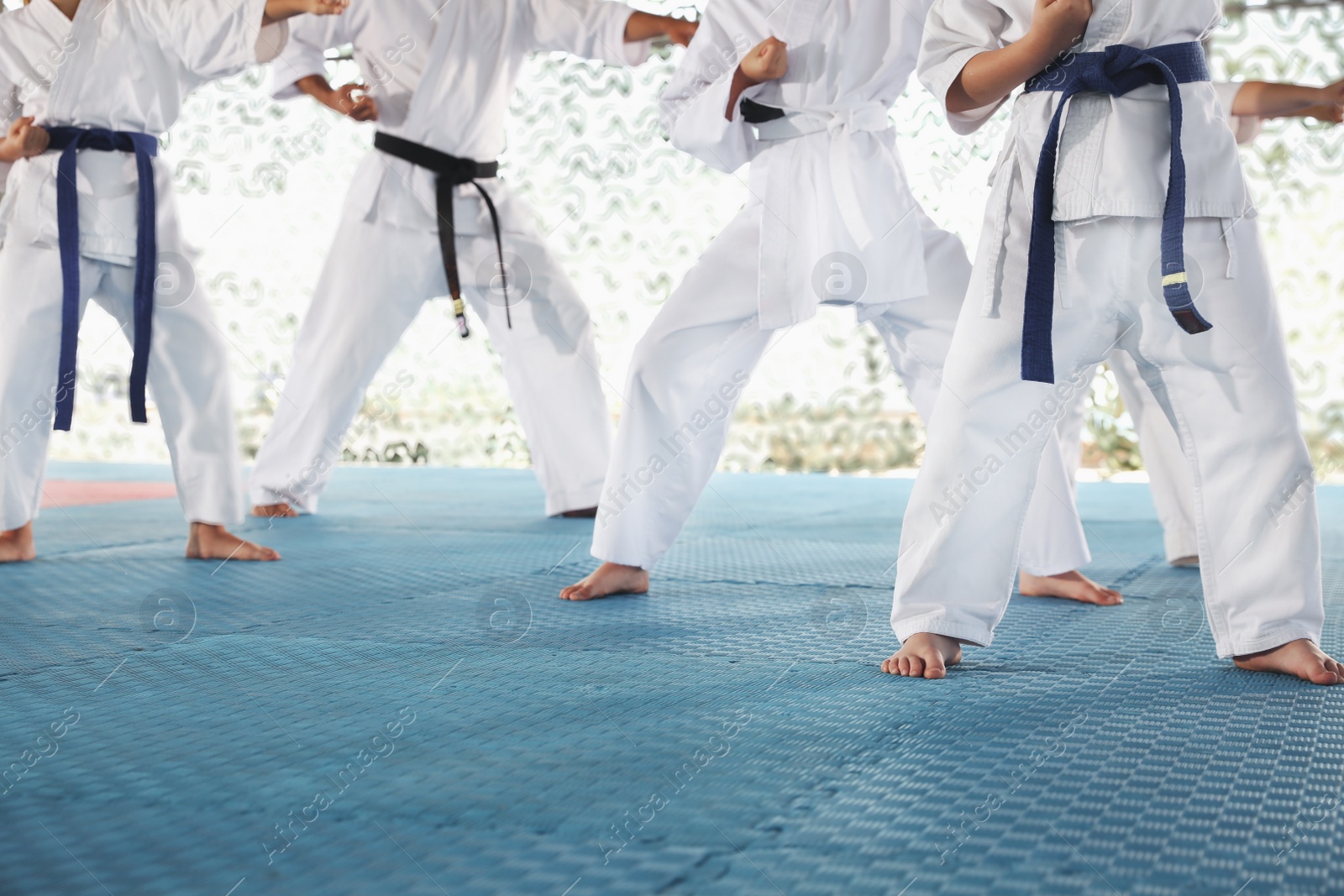 Photo of Children in kimono practicing karate on tatami outdoors, closeup