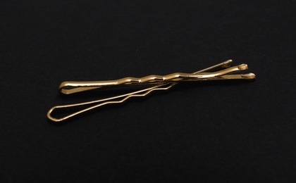 Gold invisible hair pins on black background