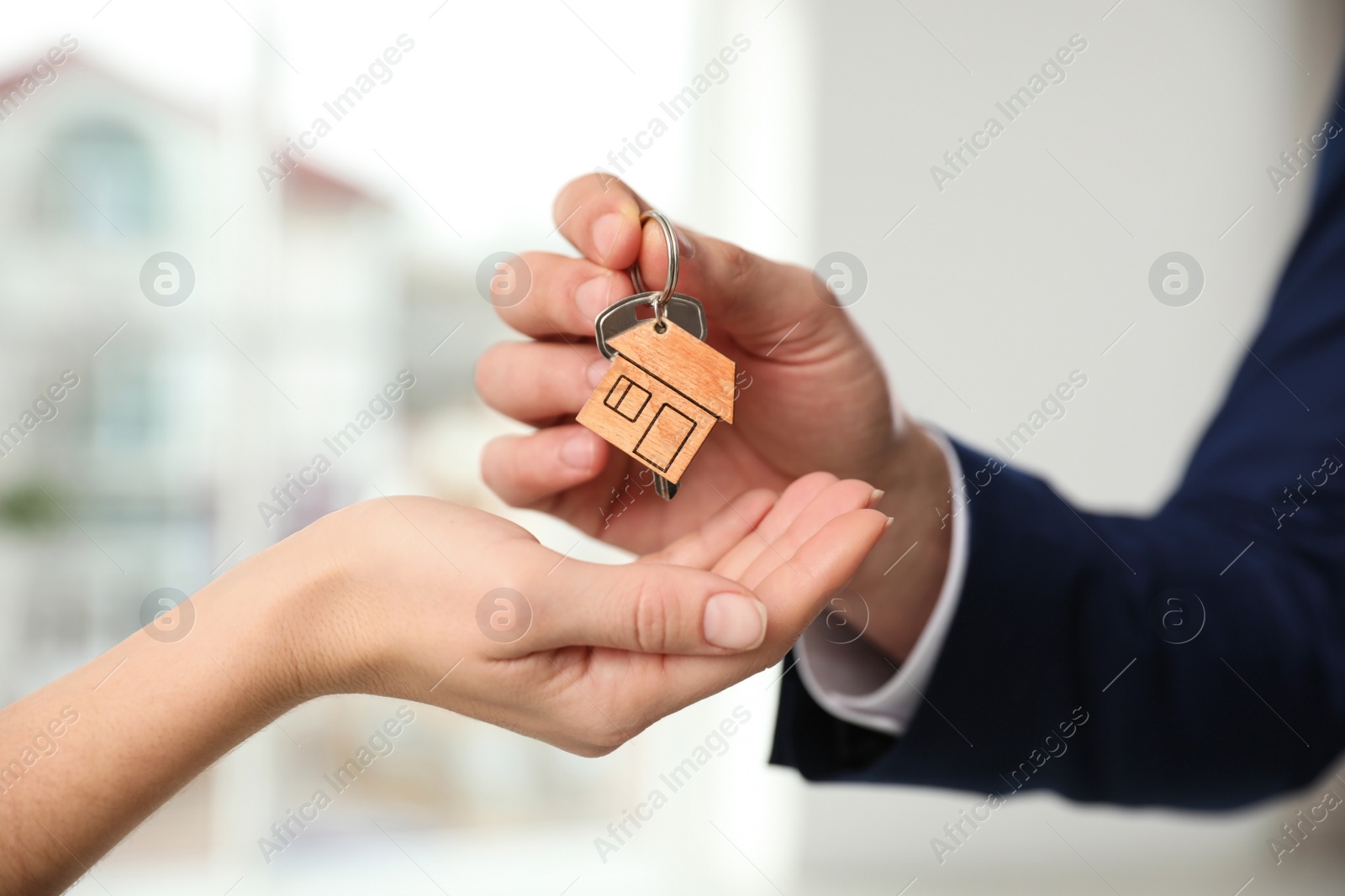 Photo of Real estate agent giving key with trinket to client in office, closeup