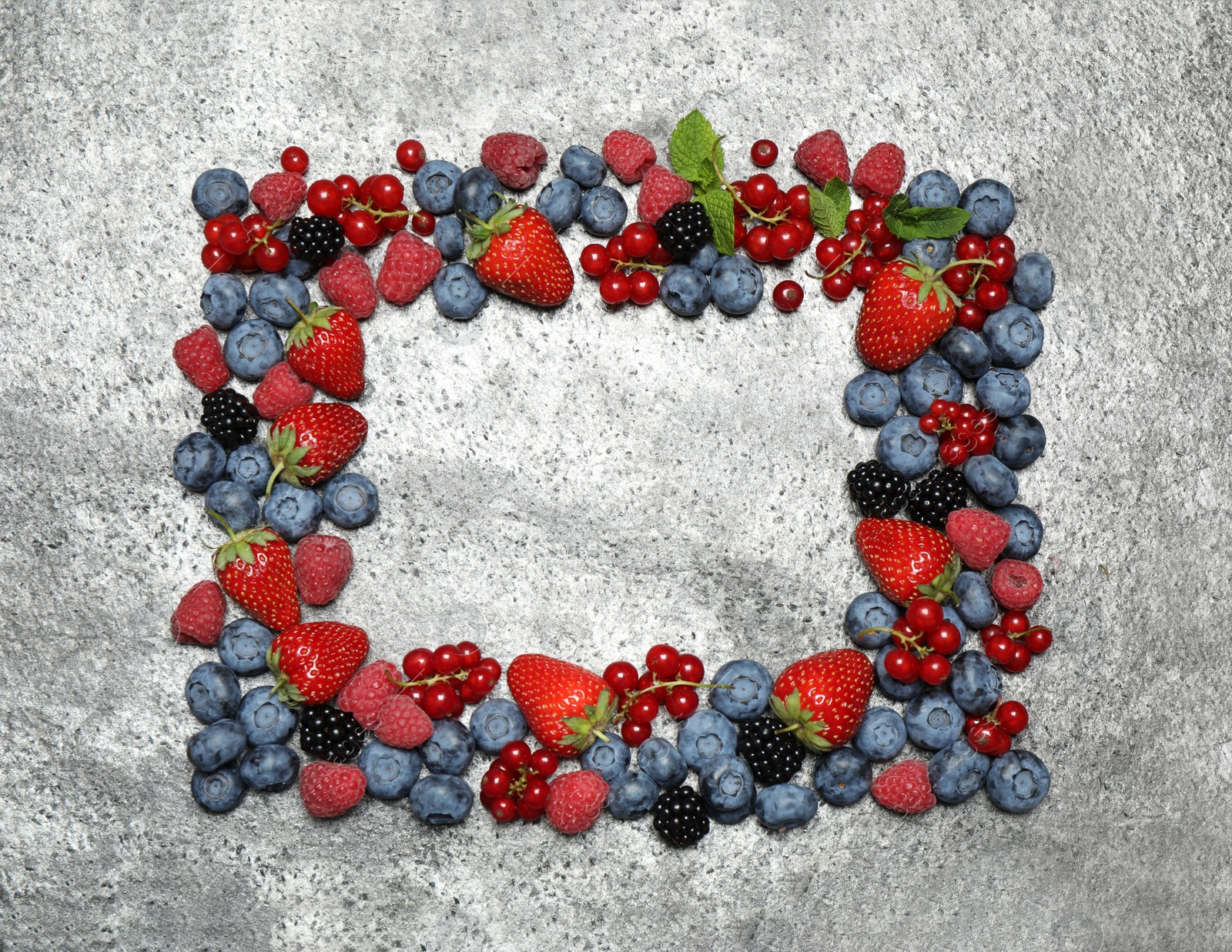 Photo of Frame of different fresh berries on grey background, top view. Space for text