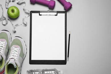 Photo of Clipboard, pencil and sports equipment on light grey background, flat lay with space for text. Personal training