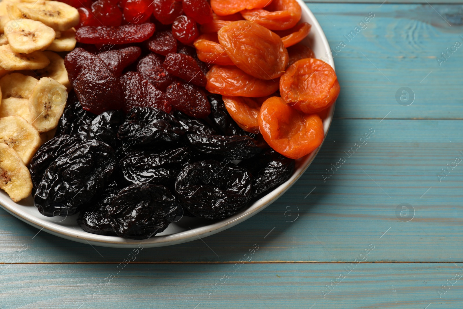 Photo of Delicious dried fruits on light blue wooden table, closeup. Space for text