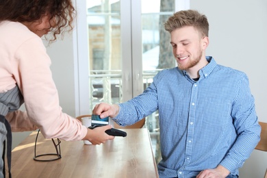 Photo of Client using credit card machine for non cash payment in cafe