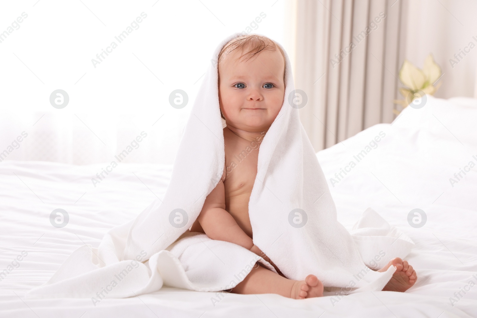 Photo of Cute little baby with soft towel on bed after bath