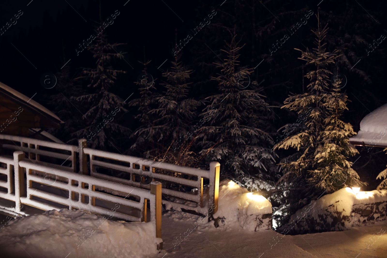 Photo of Wooden cottage near snowy forest at evening