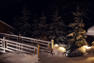 Wooden cottage near snowy forest at evening