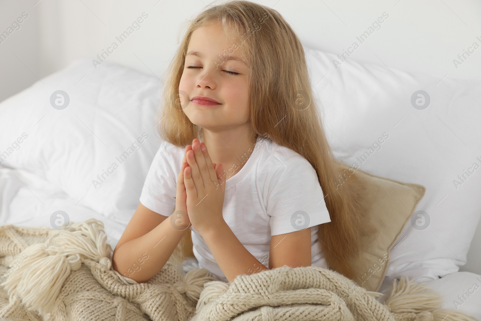 Photo of Girl with clasped hands praying in bed