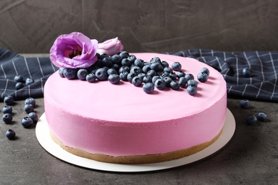 Photo of Tasty blueberry cake decorated with flowers on grey table