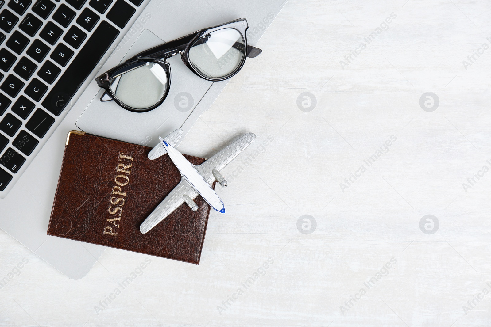 Photo of Flat lay composition with passport, laptop, toy plane and space for text on light background. Travel agency
