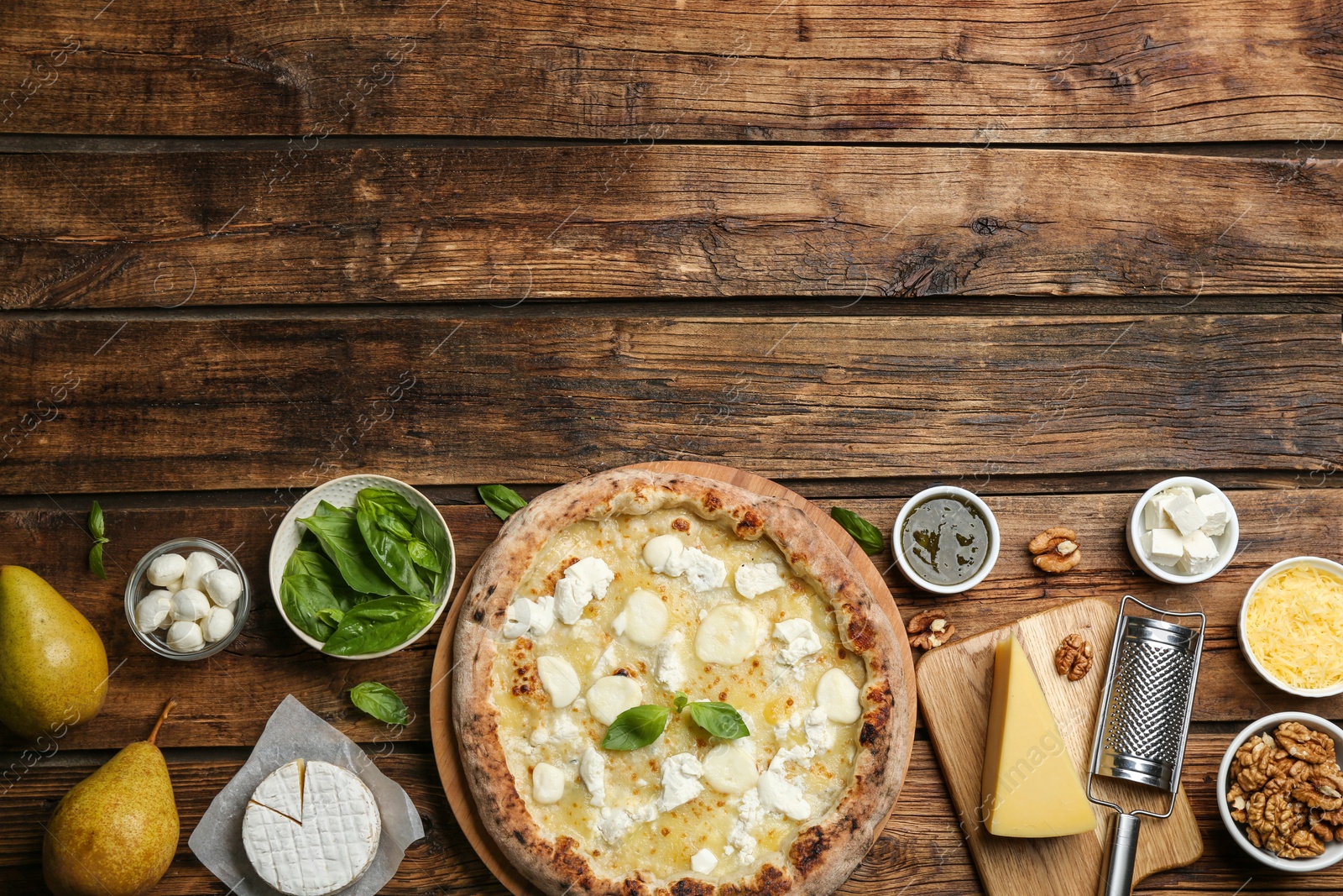 Photo of Tasty cheese pizza and ingredients on wooden table, flat lay. Space for text