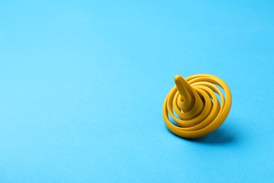 One yellow spinning top on light blue background, space for text