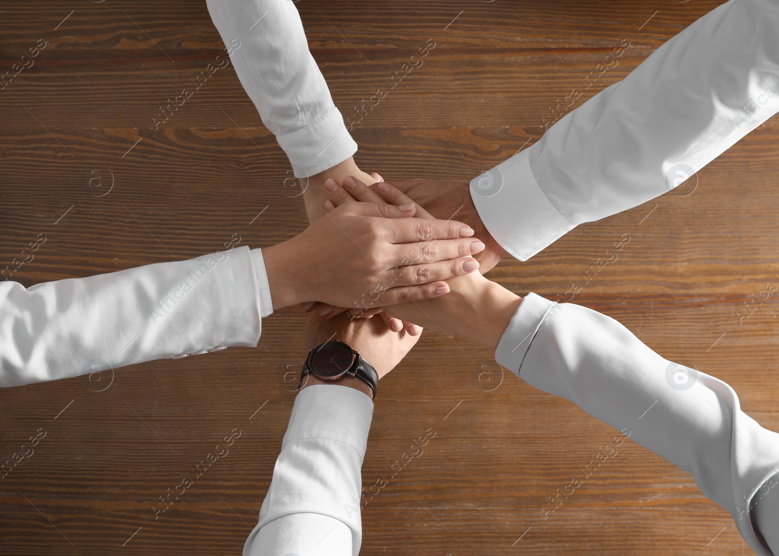 People holding hands together over wooden background, top view. Unity concept Photo of People holding hands together over wooden background, top view. Unity concept