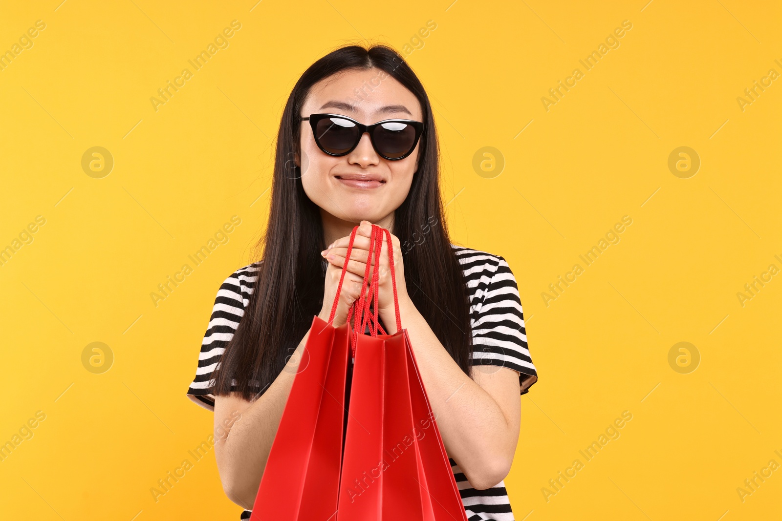 Photo of Beautiful woman with shopping bags on yellow background