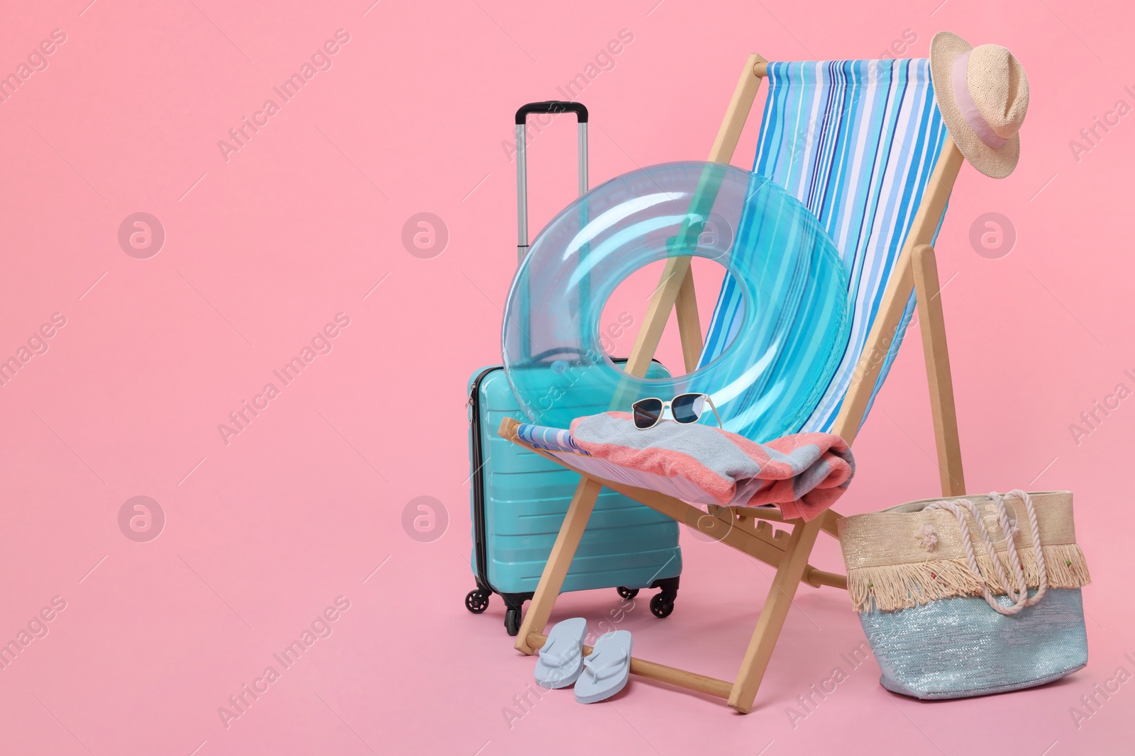 Photo of Deck chair, suitcase and beach accessories on pink background, space for text. Summer vacation