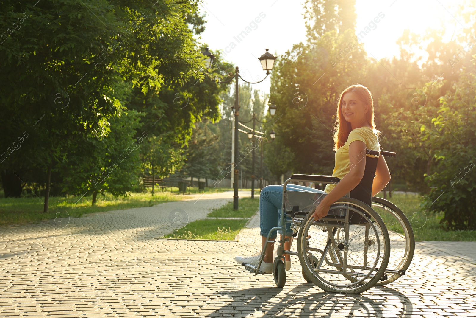 Photo of Happy woman in wheelchair at park on sunny day. Space for text