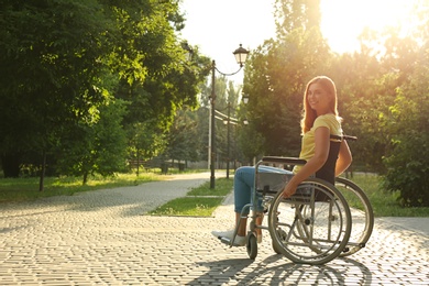 Happy woman in wheelchair at park on sunny day. Space for text