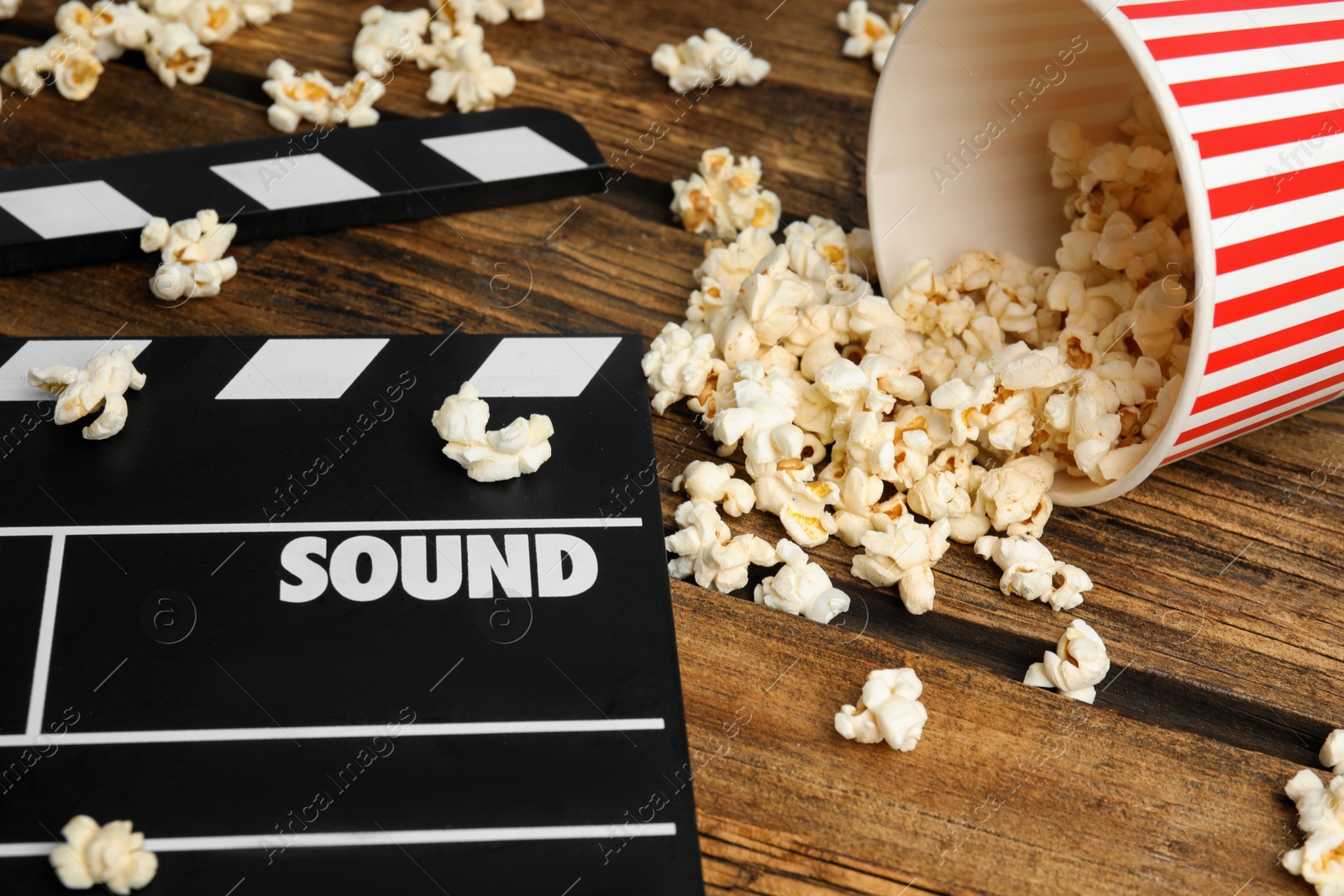 Photo of Tasty fresh pop corn and clapboard on wooden table