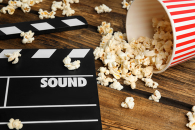 Photo of Tasty fresh pop corn and clapboard on wooden table