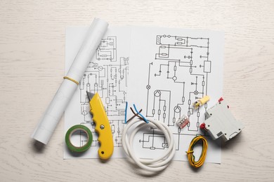 Photo of Wiring diagrams, knife, insulating tape, wires and switch on white wooden table, top view