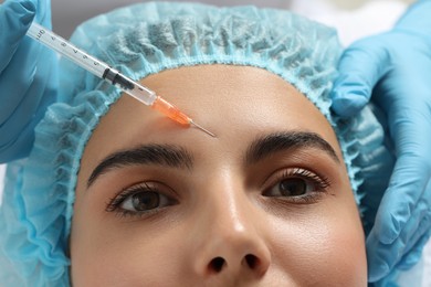Doctor giving facial injection to young woman in clinic, closeup. Cosmetic surgery