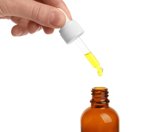 Photo of Woman holding pipette with oil over bottle on white background