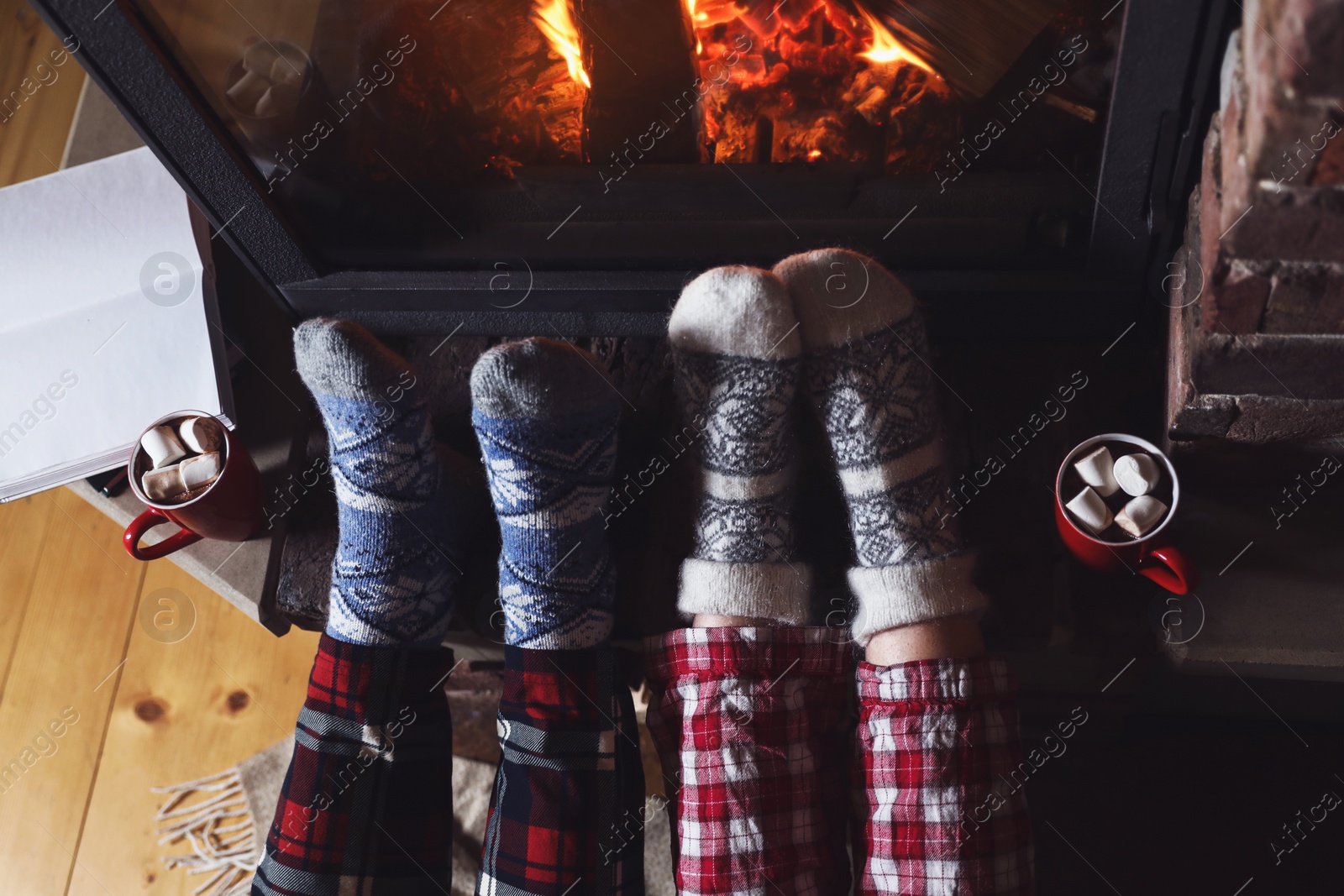 Photo of Couple in pajamas resting near fireplace indoors, closeup. Winter vacation