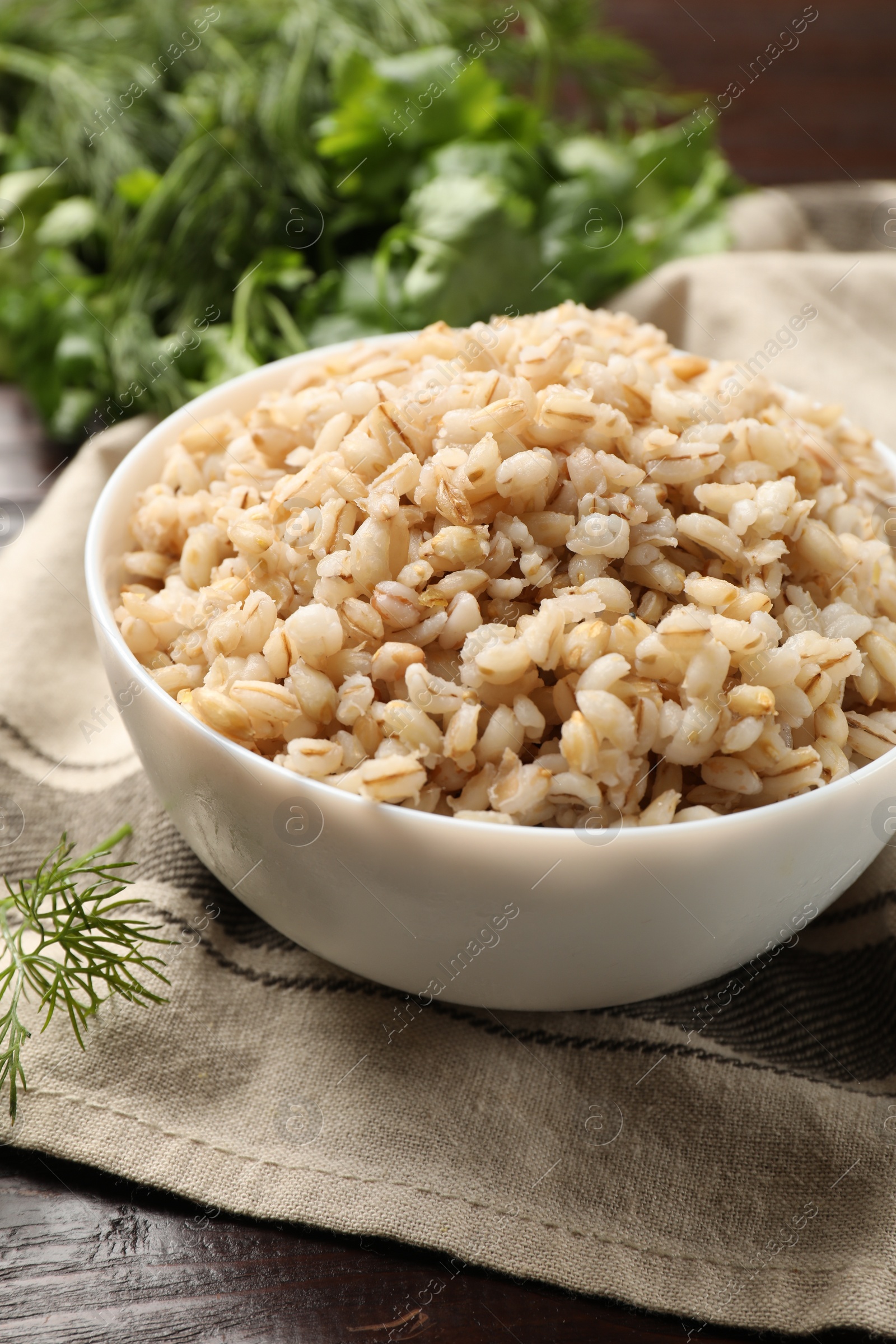 Photo of Delicious pearl barley in bowl on table, closeup