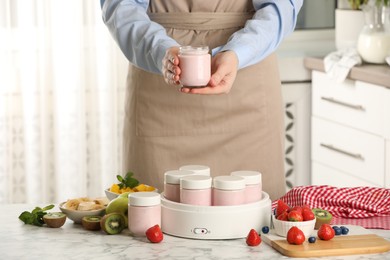 Woman making tasty yogurt at white marble table in kitchen, closeup