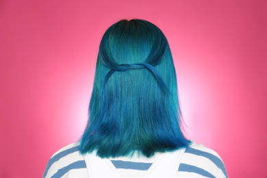 Woman with bright dyed hair on pink background, back view