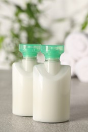 Photo of Mini bottles of cosmetic products on light grey table against blurred background, closeup