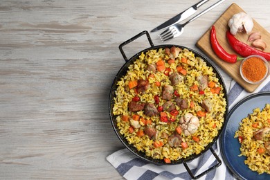 Photo of Delicious pilaf with meat, carrot and chili pepper served on wooden table, flat lay. Space for text