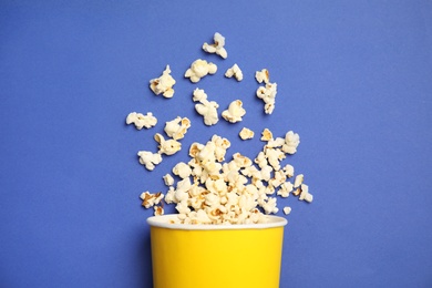 Paper cup with tasty fresh popcorn on color background, top view