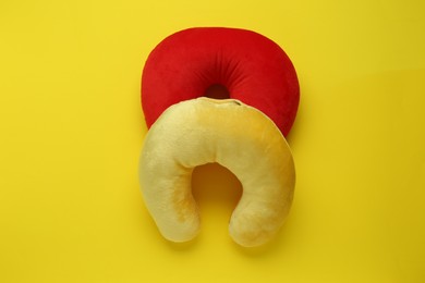 Photo of Colorful travel pillows on yellow background, top view